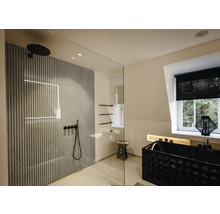 Salle de bains moderne avec douche à l'italienne en verre, panneaux muraux à lattes, robinetterie noire et baignoire noire texturée.