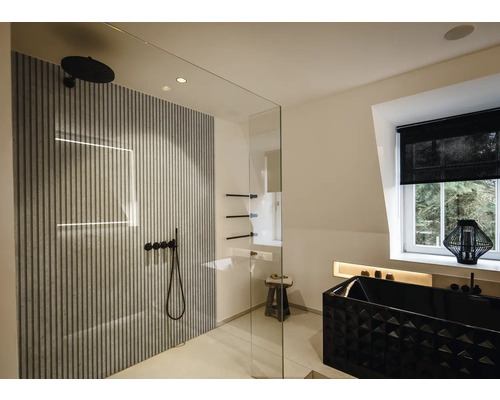 Salle de bains moderne avec douche à l'italienne en verre, panneaux muraux à lattes, robinetterie noire et baignoire noire texturée.