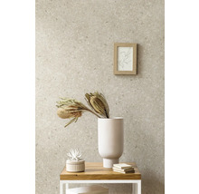 Papier peint intissé aspect pierre avec motif terrazzo dans une pièce à vivre combiné avec un vase blanc, des fleurs séchées et un cadre en bois.