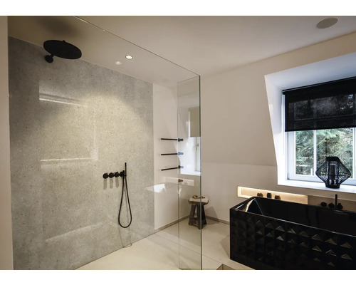 Salle de bain moderne et lumineuse avec douche à l'italienne, robinetterie noire, mur gris effet pierre et baignoire noire texturée.