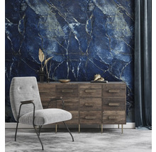 Papier peint panoramique avec motif marbre bleu dans un salon avec commode en bois et fauteuil gris.