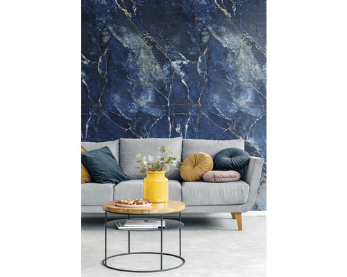 Papier peint intissé avec motif marbre bleu foncé et veines claires dans un salon moderne avec canapé gris et table basse.