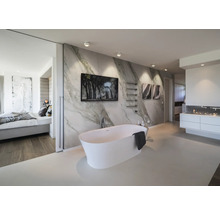 Salle de bains moderne avec baignoire îlot blanche devant un mur effet marbre, tableaux, sèche-serviettes minimaliste et éclairage lumineux.
