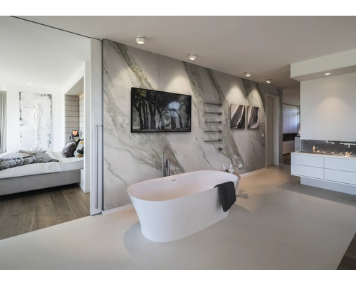 Salle de bains moderne avec baignoire îlot blanche devant un mur effet marbre, tableaux, sèche-serviettes minimaliste et éclairage lumineux.