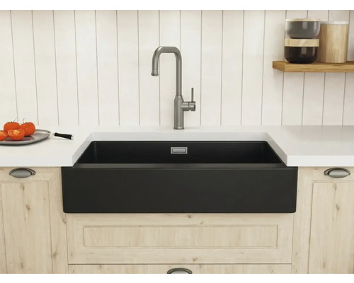 Moderne Küchenspüle im Landhausstil mit schwarzer Schürzenfront, weißer Arbeitsplatte und hoher Armatur in einer hellen, organisierten Küche.