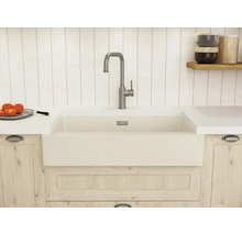 Helle Küche mit großem Keramik-Spülbecken, hoher Metallarmatur, Arbeitsplatte und Küchenschränken in Holzoptik.