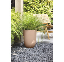 Grand pot de fleurs rond avec une texture ondulée et des graminées ornementales sur du gravier dans un jardin avec une chaise en bois.