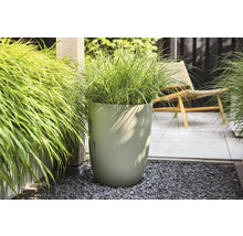 Grand pot de fleurs moderne avec structure ondulée verticale et graminées sur une terrasse lumineuse et organisée avec gravier et dalles.