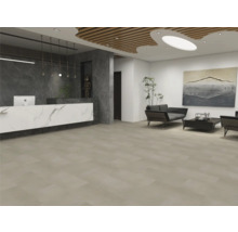 Espace de réception moderne avec de grands carreaux de sol beiges, un comptoir aspect marbre et un coin salon avec des canapés sombres.