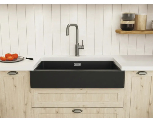 Moderne Küche mit schwarzer Schürzen-Spüle und hoher Armatur, eingebaut in helle Holzschränke mit weißer Arbeitsplatte.