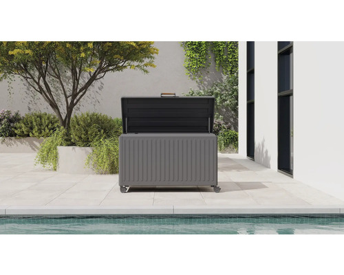 Coffre de jardin moderne en métal avec couvercle ouvert sur une terrasse claire à côté d'une piscine.