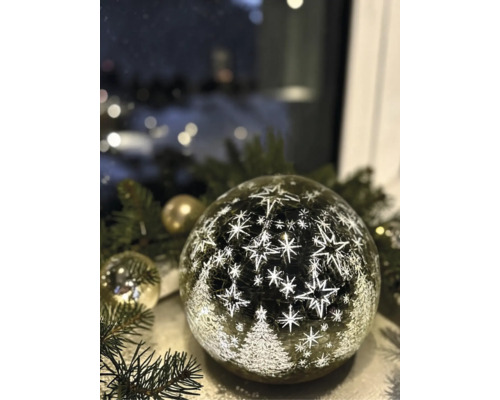 Boule LED en verre avec motif d'étoiles et de sapins de Noël sur des branches de pin.