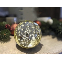 Boule de Noël lumineuse à LED en verre avec motif d'étoiles et de sapin sur une surface en bois.