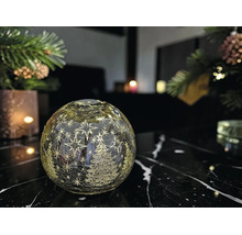 Boule lumineuse en verre LED avec étoiles et sapins sur une table en marbre sombre dans une ambiance de Noël.
