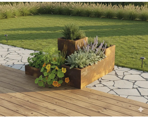 Jardinière surélevée modulaire en acier Corten dans un jardin avec des plantes, à côté d'une terrasse en bois et d'un chemin en pierre.