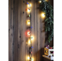 Vertikale Lichterkette mit Sternenaufsätzen an einer rustikalen Holzwand, dekoriert mit einer grünen Girlande und Weihnachtsschmuck in einer Kiste.