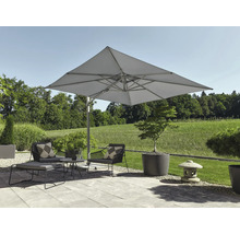 Moderner Aussenbereich mit grossem quadratischem Ampelschirm, Lounge-Sesseln und Beistelltisch auf einer hellen Steinterrasse mit Gartenblick.