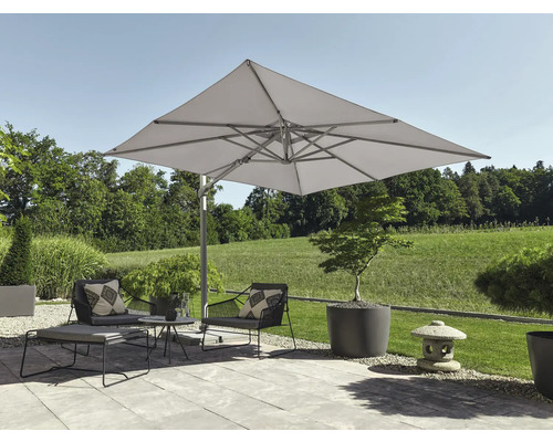 Terrasse moderne avec un grand parasol déporté carré au-dessus de fauteuils gris foncé et de jardinières, avec vue sur un paysage verdoyant.