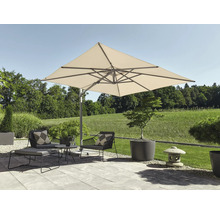 Grand parasol déporté carré sur une terrasse moderne avec fauteuils de jardin, table basse, repose-pieds et jardinières devant une pelouse.