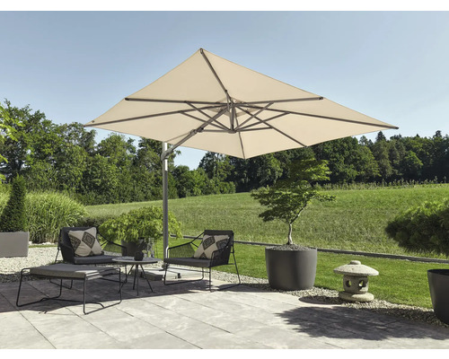 Grand parasol déporté carré sur une terrasse moderne avec fauteuils de jardin, table basse, repose-pieds et jardinières devant une pelouse.