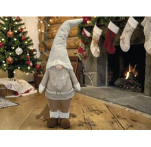 Weihnachts-Gnom Dekorationsfigur in einem festlichen Wohnzimmer mit geschmücktem Tannenbaum und brennendem Kamin.