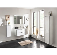 Salle de bains moderne et lumineuse avec meubles blancs, comprenant un sous-lavabo, un miroir avec éclairage et des armoires hautes.