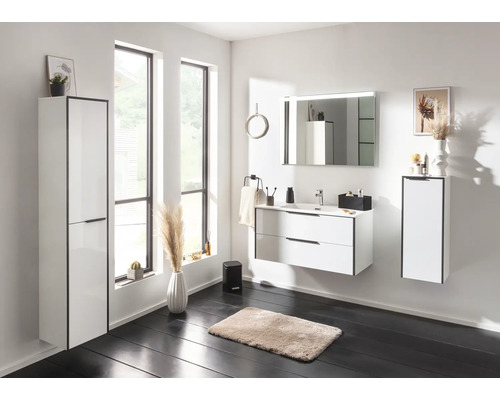 Ensemble de salle de bain moderne blanc avec meuble sous-vasque, lavabo en céramique, miroir lumineux et armoire haute dans une ambiance lumineuse.