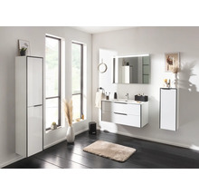 Ensemble de salle de bain moderne blanc avec meuble sous-vasque, lavabo en céramique, miroir lumineux et armoire haute dans une ambiance lumineuse.