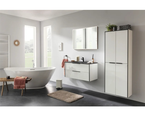 Modernes Badezimmer mit freistehender Badewanne, wandhängendem Waschtischunterschrank und hohem Badschrank in Weiss mit schwarzen Akzenten.