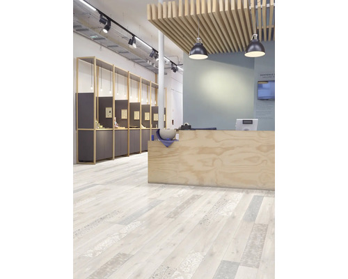 Espace de vente moderne avec sol design clair aspect bois, lames décorées, comptoir en bois et éclairage industriel au plafond.