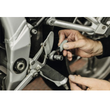 Personne utilisant un petit cliquet avec une douille pour l'entretien du cadre d'une moto.