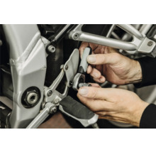 Mains utilisant un petit cliquet avec douille pour une réparation sur une moto.