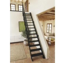 Schwarze Metalltreppe mit Geländer in einem hellen Raum mit Terrakottaboden und Holzbalkendecke.