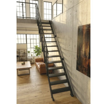 Schwarze Metalltreppe im Industriestil in einem hellen Loft mit Sichtbetonwand, Holzfußboden und Ledersofa.