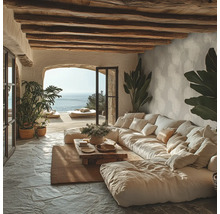 Rustikales Wohnzimmer mit grossem Modulsofa, Holzdeckenbalken, Natursteinboden und Meerblick durch eine Rundbogenöffnung.