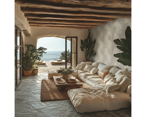Rustikales Wohnzimmer mit grossem Modulsofa, Holzdeckenbalken, Natursteinboden und Meerblick durch eine Rundbogenöffnung.