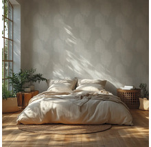 Helles Schlafzimmer mit Palmenblatt-Tapete, Holzboden, Bett mit Leinenbettwäsche, rundem Jute-Teppich und Zimmerpflanzen bei Sonnenlicht.