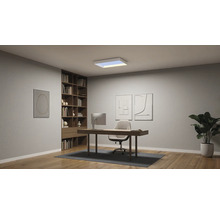Modernes Arbeitszimmer mit rechteckiger LED-Deckenleuchte, Holzschreibtisch, Bürostuhl, grossem Bücherregal und Parkettboden.