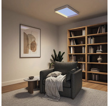 Quadratisches LED-Panel an der Decke eines modern eingerichteten Wohnzimmers mit grauem Sessel und Holzregal.
