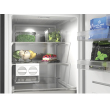 Vue intérieure lumineuse d'un congélateur organisé avec clayettes en verre, légumes, glaces, gâteau et fabrique de glaçons.