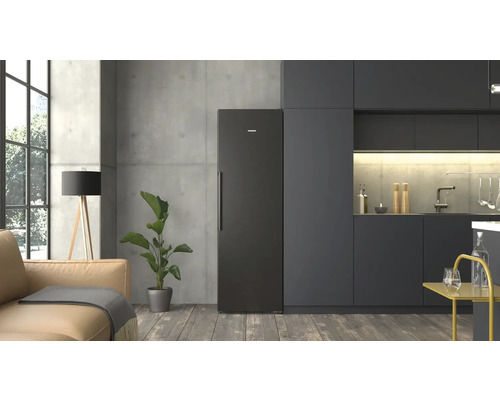 Cuisine moderne au style industriel avec réfrigérateur Siemens noir, meubles sombres, mur en béton, parquet et espace de vie adjacent.