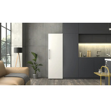 Réfrigérateur blanc posé librement dans une cuisine moderne et minimaliste avec façades sombres, mur en béton et sol en bois.