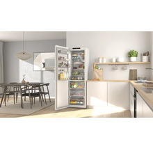 Moderne helle Küche mit offenem organisiertem Kühlschrank voller Lebensmittel und einem Essbereich mit Holztisch und Stühlen.