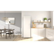 Moderner, heller Küchen- und Essbereich mit weißem Kühlschrank, Küchenzeile mit Holzplatte und Esstisch mit Holzstühlen.