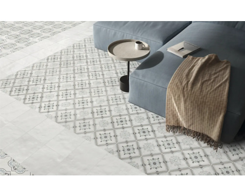 Espace de vie lumineux avec carrelage de sol à motifs décoratifs, carreaux unis en bordure et un canapé.