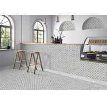 Espace de vente lumineux avec des carreaux de sol et de mur à motifs, deux tabourets de bar en bois et un présentoir à pâtisseries.