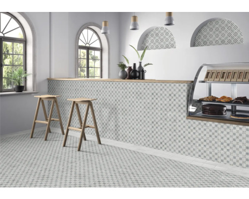 Espace de vente lumineux avec des carreaux de sol et de mur à motifs, deux tabourets de bar en bois et un présentoir à pâtisseries.