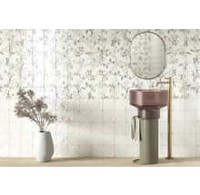 Modernes Badezimmer mit floralen Wandfliesen, freistehendem Säulenwaschbecken, hoher goldfarbener Armatur, ovalem Spiegel und Dekovase.