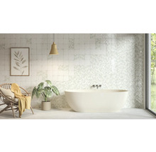 Helles Badezimmer mit freistehender Badewanne und quadratischen Wandfliesen mit floralen und schlichten Mustern.
