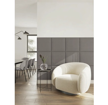 Salon moderne avec panneaux muraux rembourrés gris, fauteuil clair et coin repas à l arrière-plan.